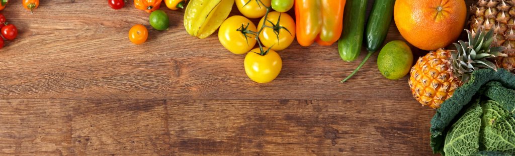 Yellow and orange fruits and vegetables on a wooden surface.