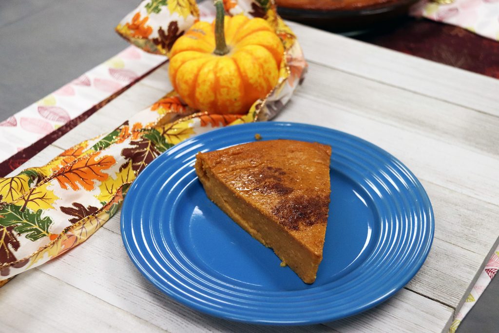 slice of pie on blue plate with ribbon and pumpkin in background