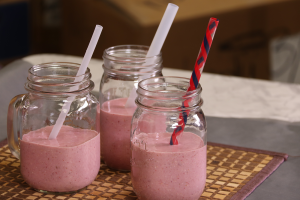 three glasses with straws, filled with pink shake