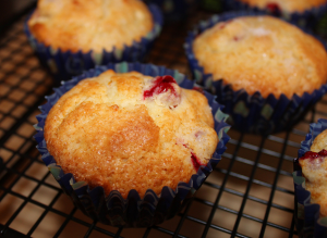 cranberry muffins in paper on a black cooling rack