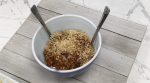 lentils and quinoa in white bowl with two metal spoons, sitting on a white wood platform