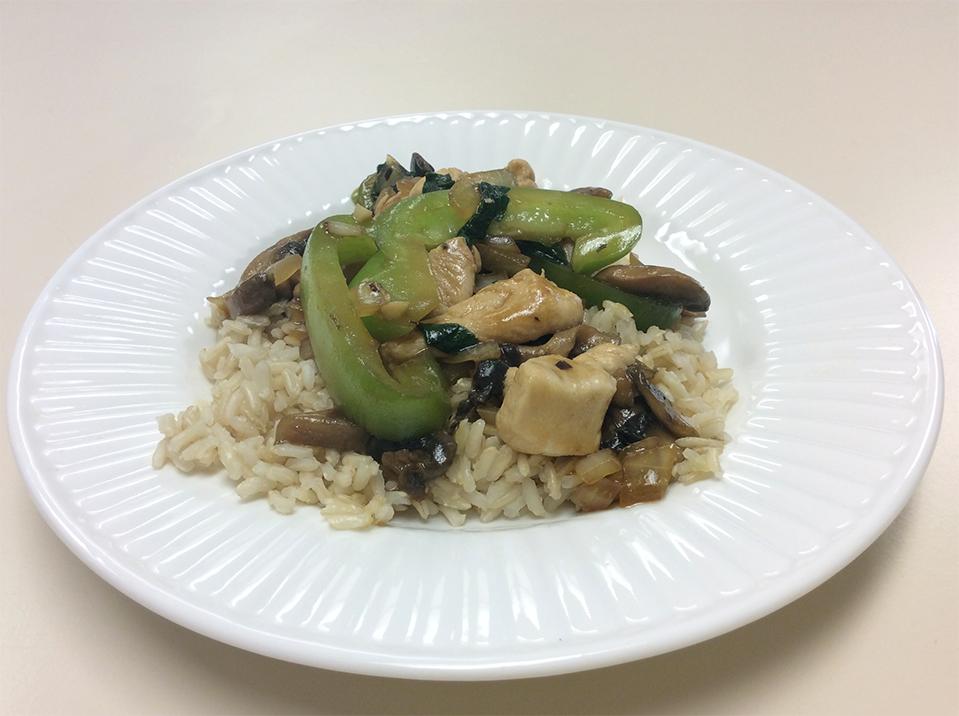 chicken pieces, green vegetables, and brown rice on a white plate.