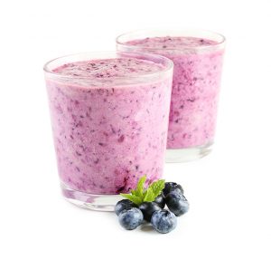 Two clear glasses filled with purple smoothie on a white background next to a bunch of blueberries