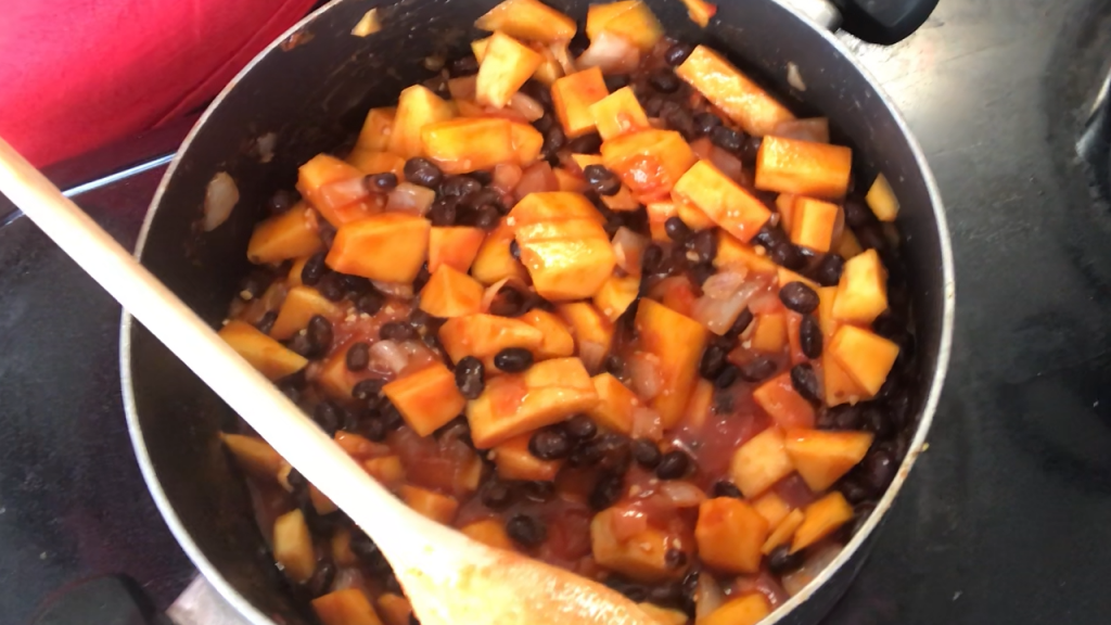 stew in black pot on black stove with white spoon in pot