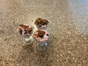 yogurt, fruit, and granola in 3 glass cups on a countertop
