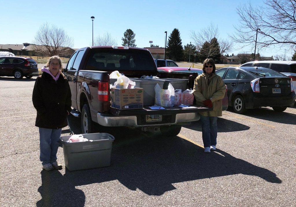 Two women standing beside a truck with boxes of food