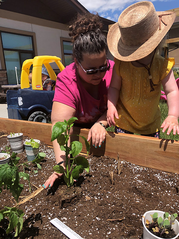 A teacher and child work in the garden