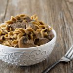 White bowl of noodles, ground meat, and mushrooms in a creamy gravy sauce