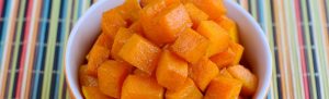Orange bowl of diced sweet potatoes sprinkled with cinnamon,