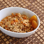 apricot granola in white bowl on checkered tablecloth