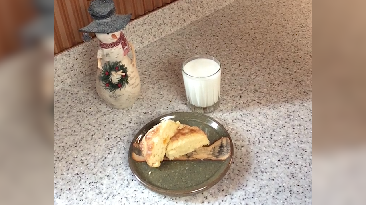two scones on plate with glass of milk and ceramic snowman decoration