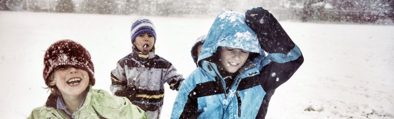 Four kids wearing coats playing in snow.