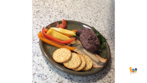 hummus, sliced peppers, and crackers on a plate