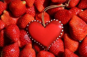 heart ornament on pile of fresh strawberries