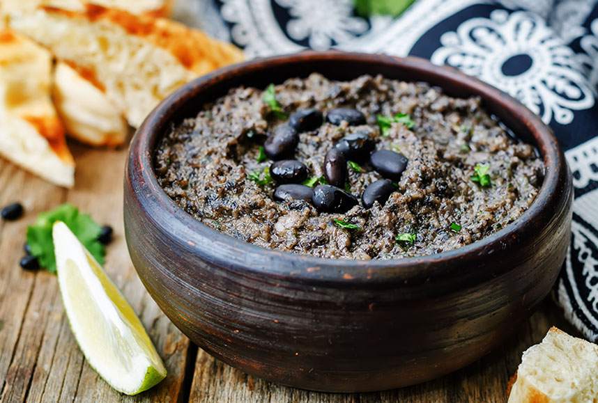 Dark brown bowl of black bean hummus