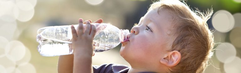 young boy drinking water out of a bottle