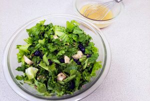 salad in a glass bowl with a bowl of vinaigrette