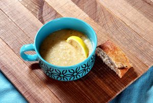 Parsnip soup in a blue bowl with bread and lemon