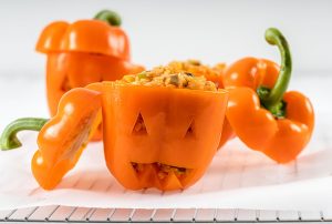 Orange bell peppers stuffed and carved like a jack-o-lantern.