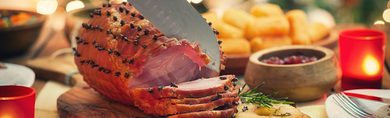 Holiday ham being sliced on cutting board