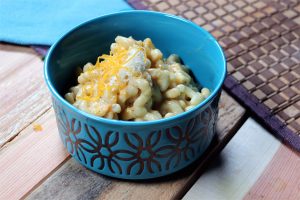 Bowl of butternut mac and cheese topped with cheese