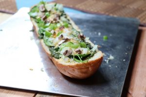 French bread topped with pesto, green vegetables, and cheese