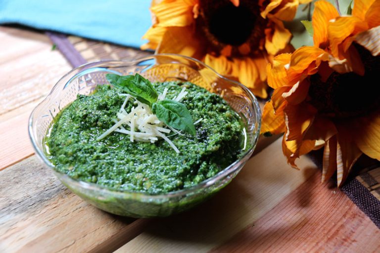 Pesto in a bowl topped with cheese and basil