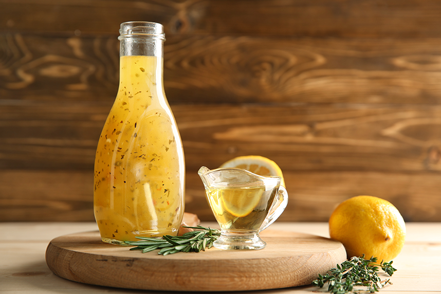 marinade in bottle on top of wooden board with decorative herbs and lemons