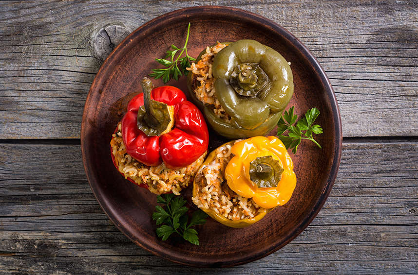 overhead view of cooked stuffed bell peppers on plate on wooden table