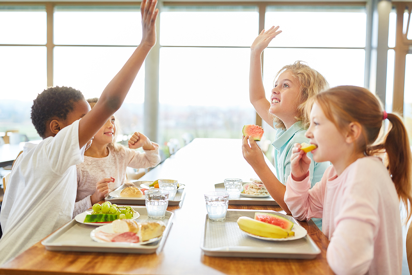 children high fiving while eating lunch