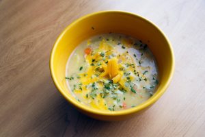 Bowl of potato soup topped with cheese and herbs