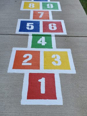 Colorful hopscotch stencil painted on the sidewalk.