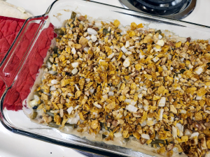 Glass casserole dish with green beans and a crunchy walnut topping