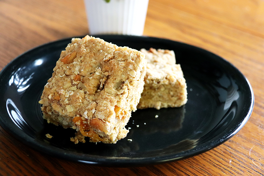 Breakfast bars artfully stacked on dark plate on wooden table.