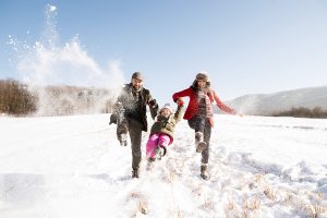 father and mother having fun with their daughter, playing in the snow. Sunny white winter nature.