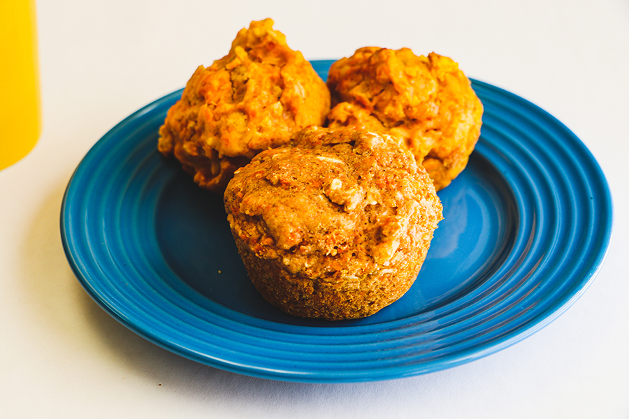 sweet potato carrot muffins on blue plate on white background. Coffee mug in the background.