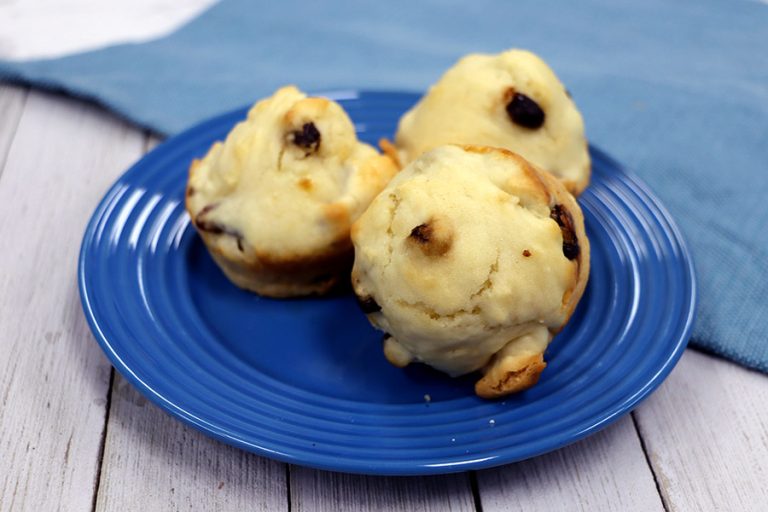 Three walnut and raisin muffins on a blue plate with a light wooden background