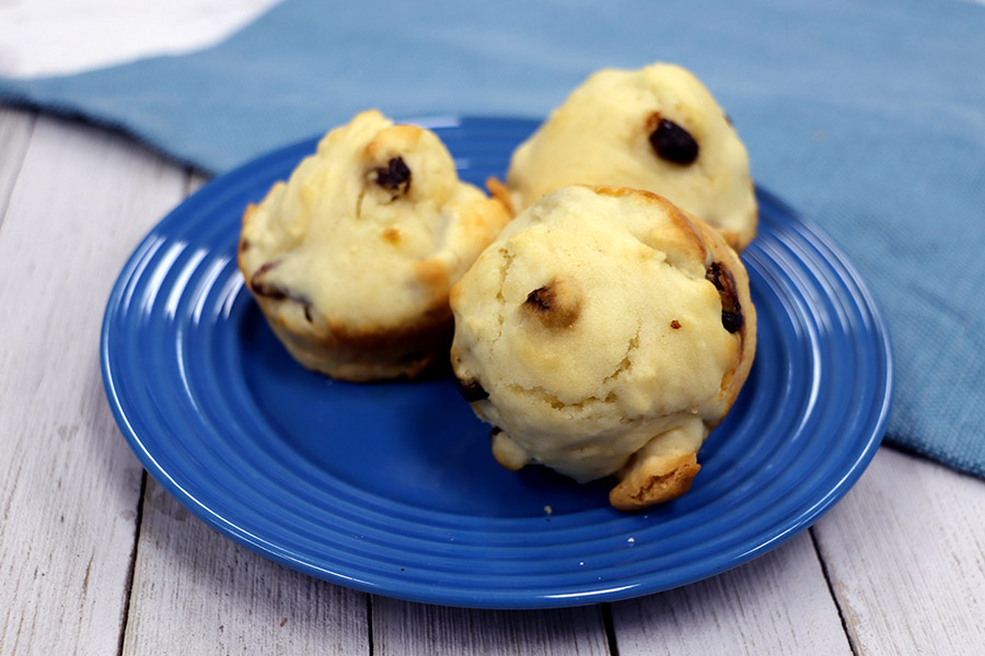 Three walnut and raisin muffins on a blue plate with a light wooden background