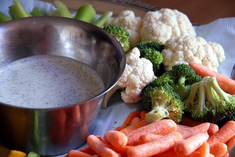 Silver bowl of white dip surrounded by vegetables