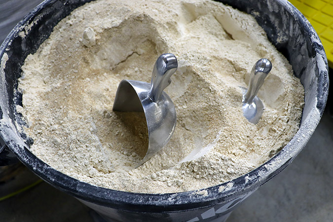 A bin of flour with two metal scoops in it.