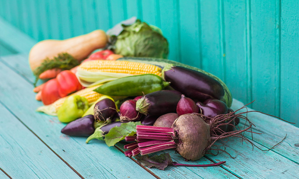 Colorful summer produce on turquoise colored wooden table with a turquoise background.