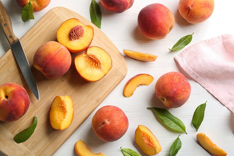 Peaches on a counter and cutting board, some cut open