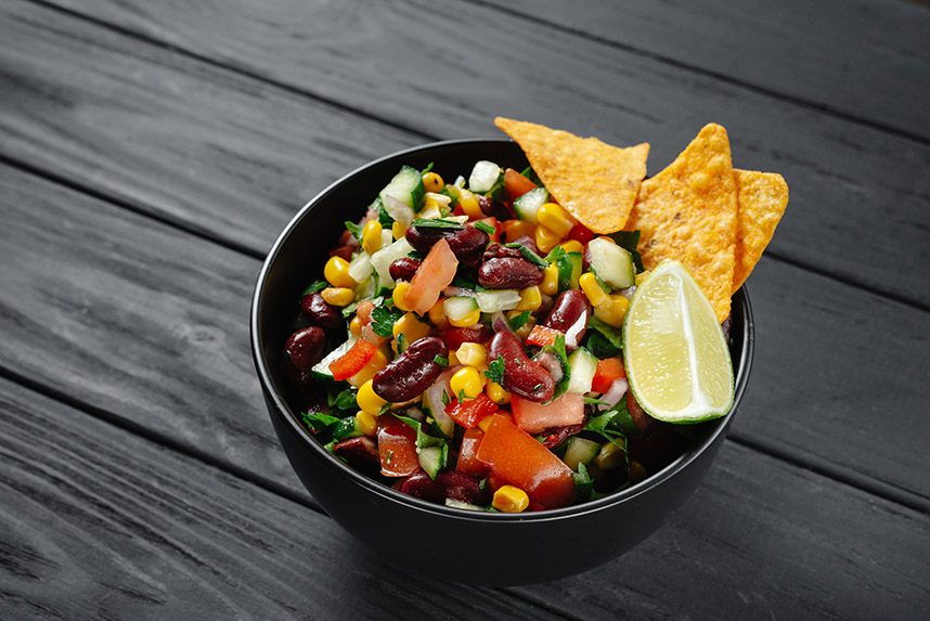 Bowl of salsa made with beans, tomatoes, corn, and peaches.