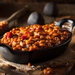 Baked beans in a dark iron skillet on a wooden background