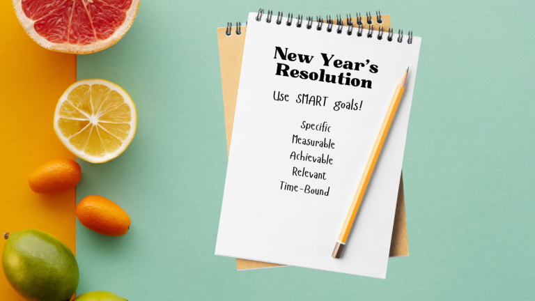 Tea and orange background with fruit and a notebook that says New Year's Resolution