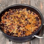 Skillet of grains and beans topped with cheese