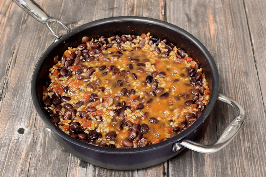 Skillet of grains and beans topped with cheese