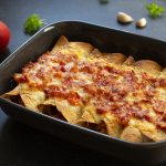 Baking dish of enchiladas with red sauce and cheese on top