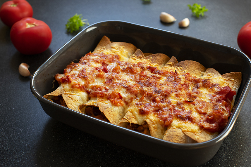 Baking dish of enchiladas with red sauce and cheese on top