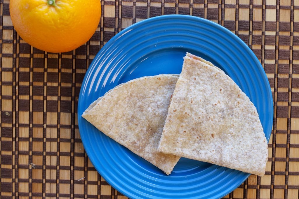 Quesadilla on a blue plate next to an orange